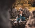 Zoomed full body portrait of an attractive brunette sitting on a well at the Rajcica wells natural landmark. Girl wearing jeans Royalty Free Stock Photo