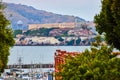 Zoomed in view of Alcatraz Island between trees with distant mountain and boats docked in bay