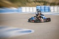 zooming effect of a teenager driving a kart at the exit of a curve of a karting circuit, face of speed and concentration while