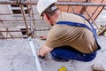 Civil engineer is marking point with pencil on concrete at building site