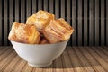 Bowl Of Freshly Baked Zuzu Square Sesame Puff Croissant Pastry Set On Rustic Bamboo Place Mat