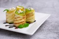 Zucchini appetizer rolls with cream cheese and basil on white plate on gray background. Fried vegetable marrow sushi rolls.