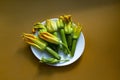 Zucchini flowers in white plate on the brown background. Flat lay, copy space Royalty Free Stock Photo