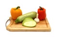 Zucchini, head of garlic and a pair of ripe yellow and orange sweet peppers on a cutting board on a light background.