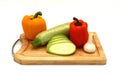 Zucchini, head of garlic and a pair of ripe yellow and orange sweet peppers on a cutting board on a light background.