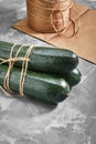 Zucchini lying on a gray background from behind ecological packaging. Delivery of products, copies of space, photos for