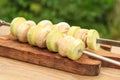 Zucchini and mushrooms on metal skewers on wooden chopping board