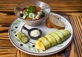 Zucchini omelette with fresh salad, bread and sauce on a plate on wooden table Royalty Free Stock Photo