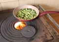 zucchini in a pan are cooked over a wood-burning stove