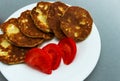 Zucchini pancakes with tomatoes stack on white plate. Vegetable harvesting concept