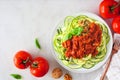 Healthy plant-based zucchini pasta topped with meatless walnut cauliflower bolognese, top view table scene on a white marble backg