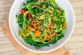 Zucchini spaghetti salad with yellow tomatoes, red pepper, onion, seasame seeds, cilantro in white bowl. Fresh salad on table. Royalty Free Stock Photo