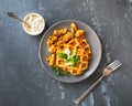 Zucchini waffles with cheese and sauce on a gray plate on a gray background