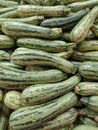 Zucchinis or Courgettes piled over each other on a market gondola.