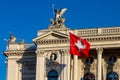 Zurich Opera House and its rooftop sculptures with the flag of Switzerland against a clear blue sky Royalty Free Stock Photo