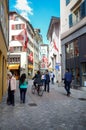 Zurich, switzerland - May, 2018: Cobblestone street in Zurich with people shopping and walking, boutique shops, swiss flags on old Royalty Free Stock Photo