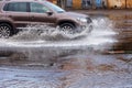 Ãâriving car on flooded road during flood caused by torrential rains. Cars float on water, flooding streets. Splash on car.