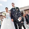 Happily Just Married. An action blur of happy bride and groom walking out of church after wedding with confetti being thrown Stock Photo