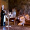 Wine and glass on the bar. A bottle of red wine and a wineglass on the bar, tables and seats in the background Stock Photo