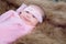 0-1 month Asian newborn baby lie down on brown fur in studio, toddler infant open eye seeking some voice near her, baby make funny