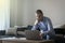 09.06.2022 - Pleven,Bulgaria - Young attractive man sitting on sofa at home working on laptop online, using internet, smiling,