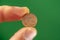 1 euro cent coin face held between thumb and index finger.