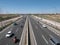 A-1 motorway towards Madrid, six entry and exit lanes with vehicles and motorcycles and service roads on the sides with streetligh