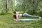 1 white girl in green top and green leggings makes a plank in nature among the trees