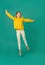 1 white teenage girl 10 years old in a yellow blouse and white pants jumps on a green background