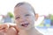 1 year baby boy showing his first teeth at swiming pool