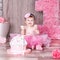 1 year baby girl in pink dress with her first birthday cake