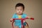 1 year old Chinese Asian boy wearing rompers riding a bicycle