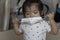 A 1-year-old girl, Asian, tries to wear a mask to protect herself against the virus