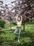 1 young woman in sportswear stands in a tree pose in a blooming Apple orchard, yoga, spring