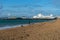 10/09/2019 Portsmouth, Hampshire, UK A middle aged woman walking her dog on a pebble beach with south parade pier southsea in the