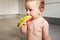 10-month-old baby sitting on the floor of her kitchen nibbling a slice of watermelon getting dirty all over