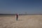 A 10 year old boy in a white sweatshirt and orange vest launches a kite on a deserted beach in solitude