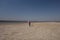 A 10 year old boy in a white sweatshirt and orange vest launches a kite on a deserted beach in solitude