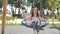 A 10-year-old girl is swinging on a round wicker swing on a playground in the courtyard of a house in a new neighborhood