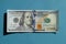 100 dollar bill at the center on the blue background. Conceptual photo, minimalistic design of currency