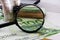 100 euros through a magnifier on a background of euro banknotes and coins.