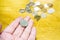 100 Yen Japanese coins on hand with blurry Japanese coins heap on wooden table background