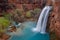 The 100ft Havasu Falls cascades in to a beautiful deep blue pool beneath, surrounded by thick, green vegetation.