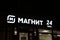 11.21.2020 Syktyvkar, Russia, glowing white signboard Magnit in dark backgound