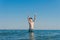 13 years old boy raises his hands standing up in the sea waves. Concept of family summer vacation