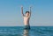 13 years old boy raises his hands standing up in the sea waves. Concept of family summer vacation