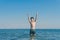 13 years old boy raises his hands standing up in the sea waves. Concept of family summer vacation