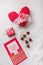 14 February Heart shaped chocolates, fabric heart toy, red candle on white paper, postcard. Valentines day sweets and presents