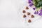 14 February Heart shaped chocolates, violet flowers on white paper background. Valentines day sweets. Copy space