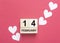 14 February inscription on wooden cube calendar and heart shapes papers on red or pink
